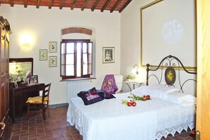 Un dormitorio con cama, escritorio, silla, ventana y lámpara fijada a la pared.