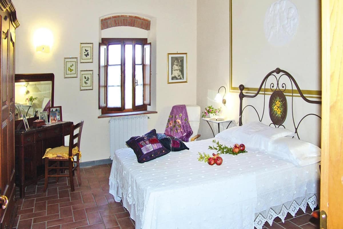 Un dormitorio con cama, escritorio, silla, ventana y espejo.