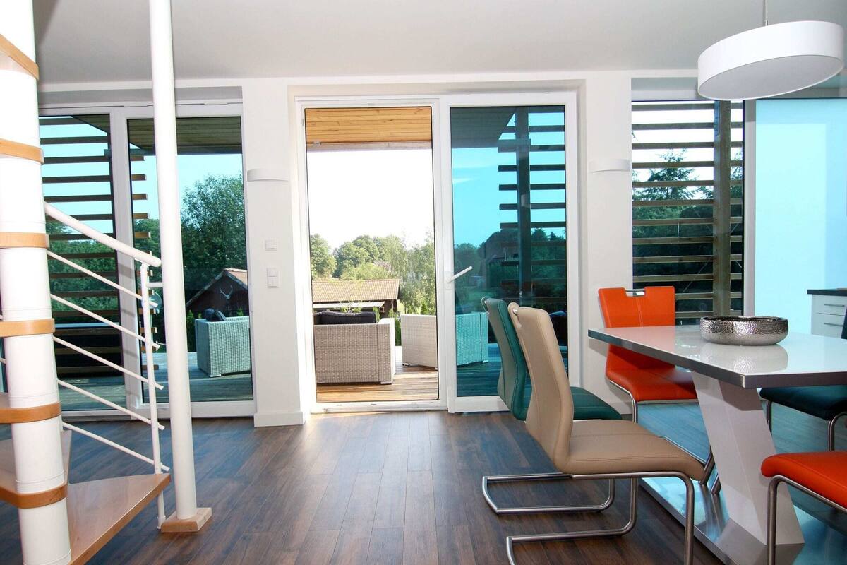 A modern kitchen with a dining area, a staircase, and a view of the outdoors.