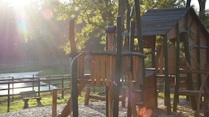 Ein Spielplatz mit einer Kletterkonstruktion und einem hölzernen Spielhäuschen.