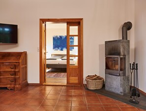 Ein Zimmer mit einem Holzkleiderschrank, einem Fernseher, einem Bett mit einem blauen abstrakten Gemälde und einem Kaminofen.