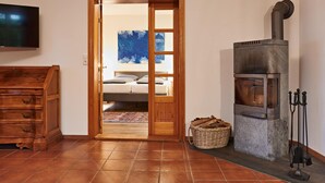A room with a bed, a wooden dresser, a fireplace, and a television mounted on the wall. - Holiday Home Oliver, Wendorf (Kuhlen-Wendorf)