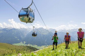 Eine Seilbahn mit dem Aufdruck "wild kogel bahnen" in einer Berglandschaft, mit Wanderern.