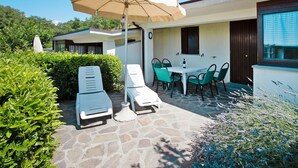 Un patio con poltrone da relax, un tavolo e un ombrellone.