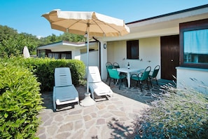 Un patio con sillones de descanso, una mesa y una sombrilla.