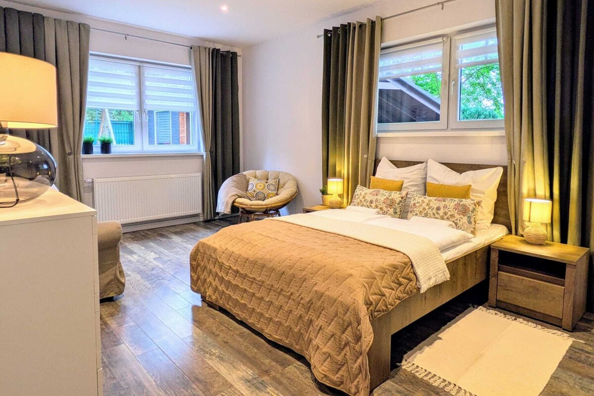 A bedroom with a bed, bedside tables, a chair, and a window with curtains.