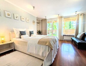 A bedroom with a bed, bedside tables, a sofa, and a window with curtains. - Comfortable Apartment for 10 People With a Private Sauna, Kolobrzeg (Kołobrzeg)