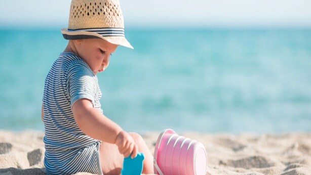A child playing with sand toys on a beach.