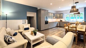 A modern living room with a sofa, coffee table, and dining area with chairs and a table.