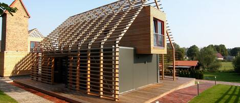 A modern building with a sloped roof, wooden exterior, and a small balcony.