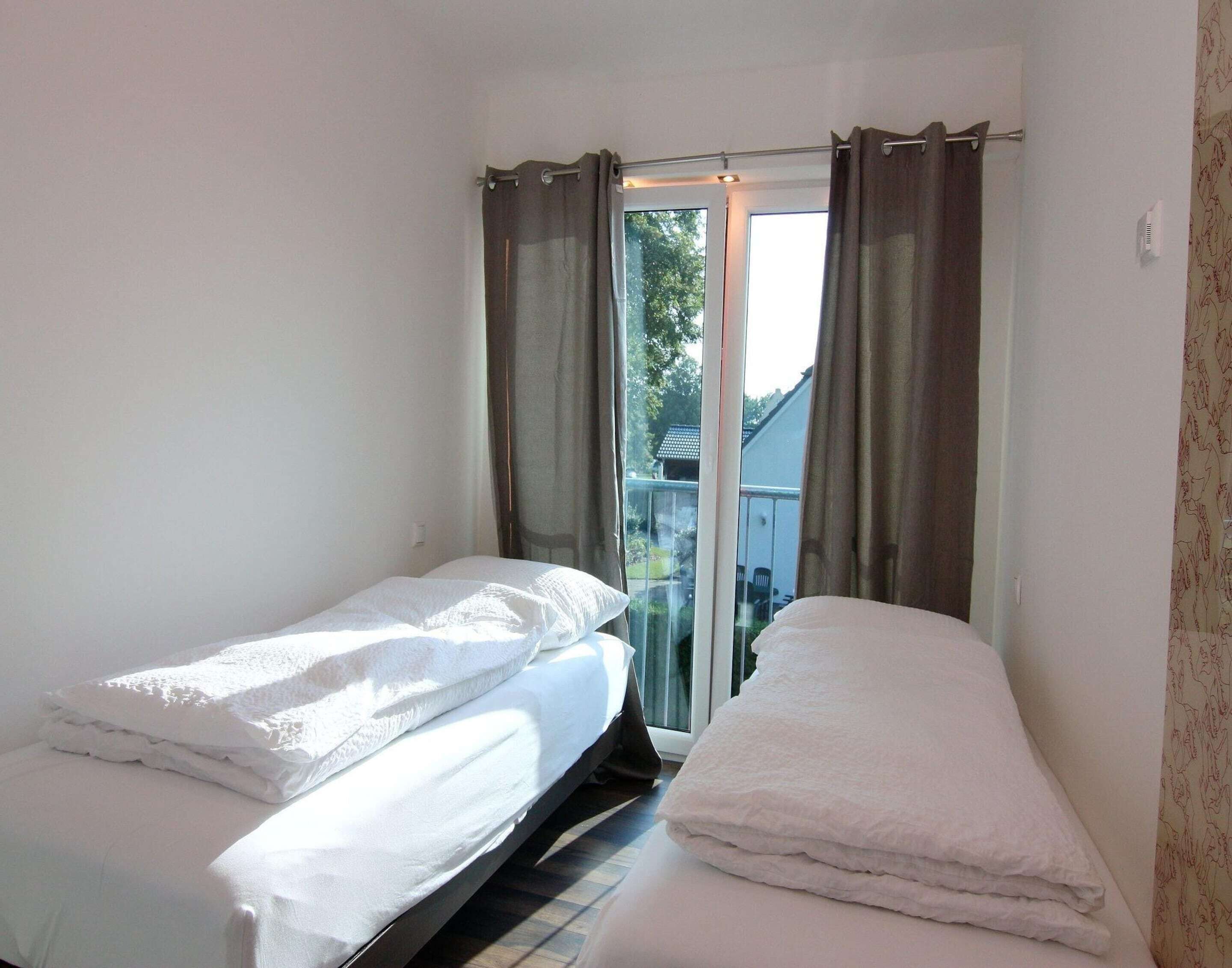 Une chambre avec deux lits, une fenêtre avec des rideaux et une vue sur l’extérieur.