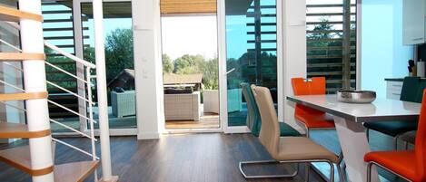 A modern kitchen with a dining area, a staircase, and a view of the outdoors.