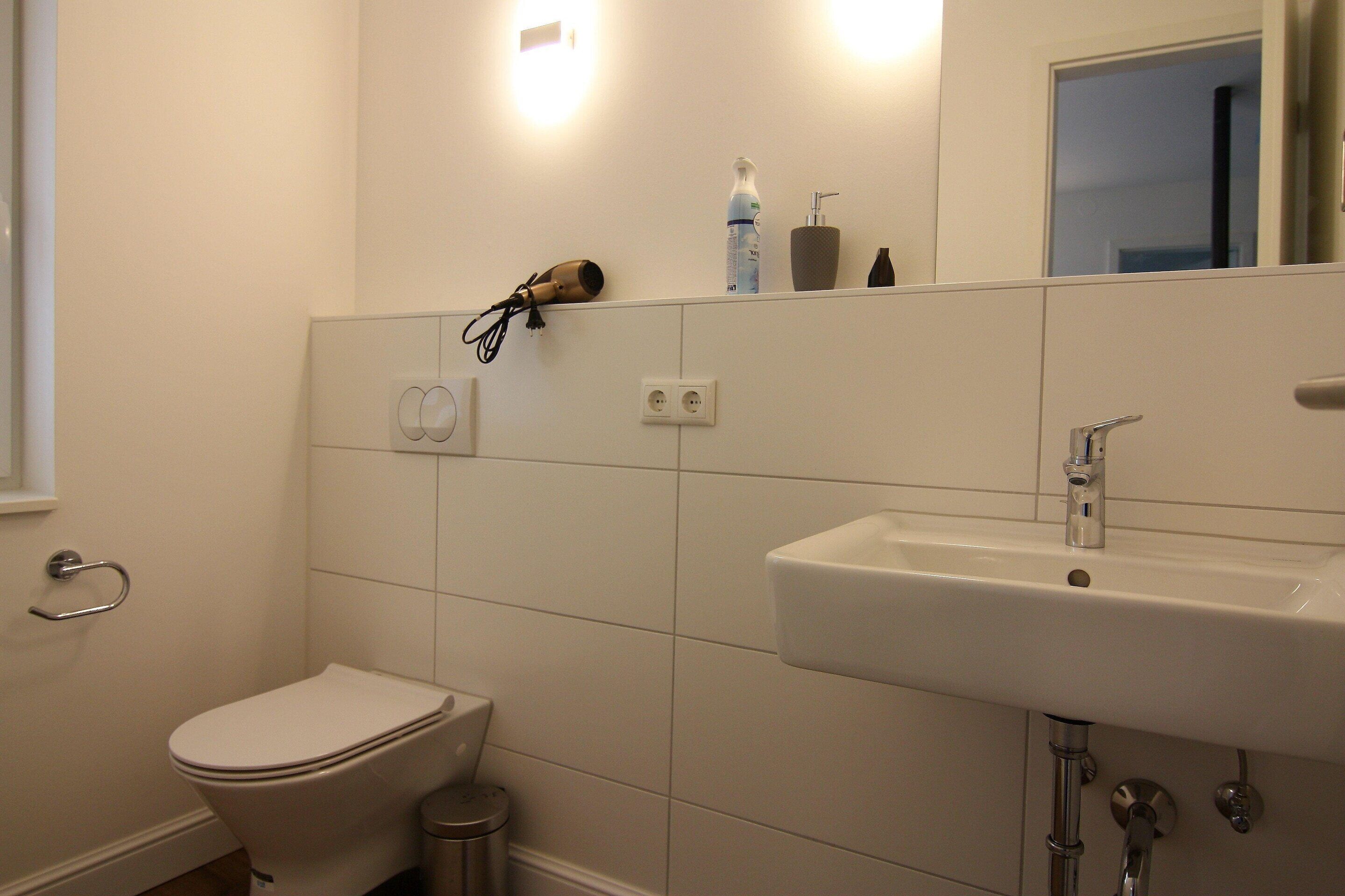 Un bagno con servizi igienici, lavabo e asciugacapelli a muro.