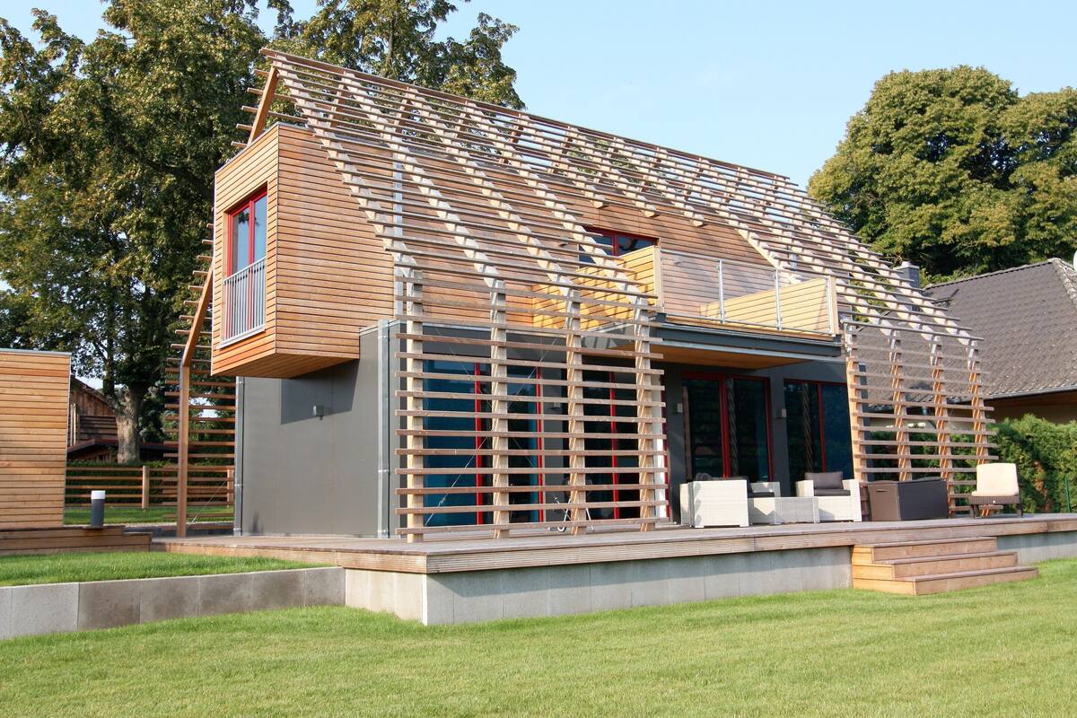 A modern house with a sloped roof, a wooden deck, and a small outdoor seating area.