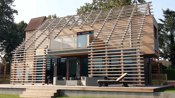 Una casa moderna con fachada de madera en listones, ventanas amplias y techo plano.
