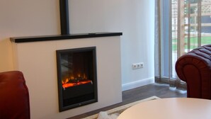 A modern living room with a fireplace, a red leather chair, and a large window with a view of the outdoors. - Chalet, Wendorf (Kuhlen-Wendorf)