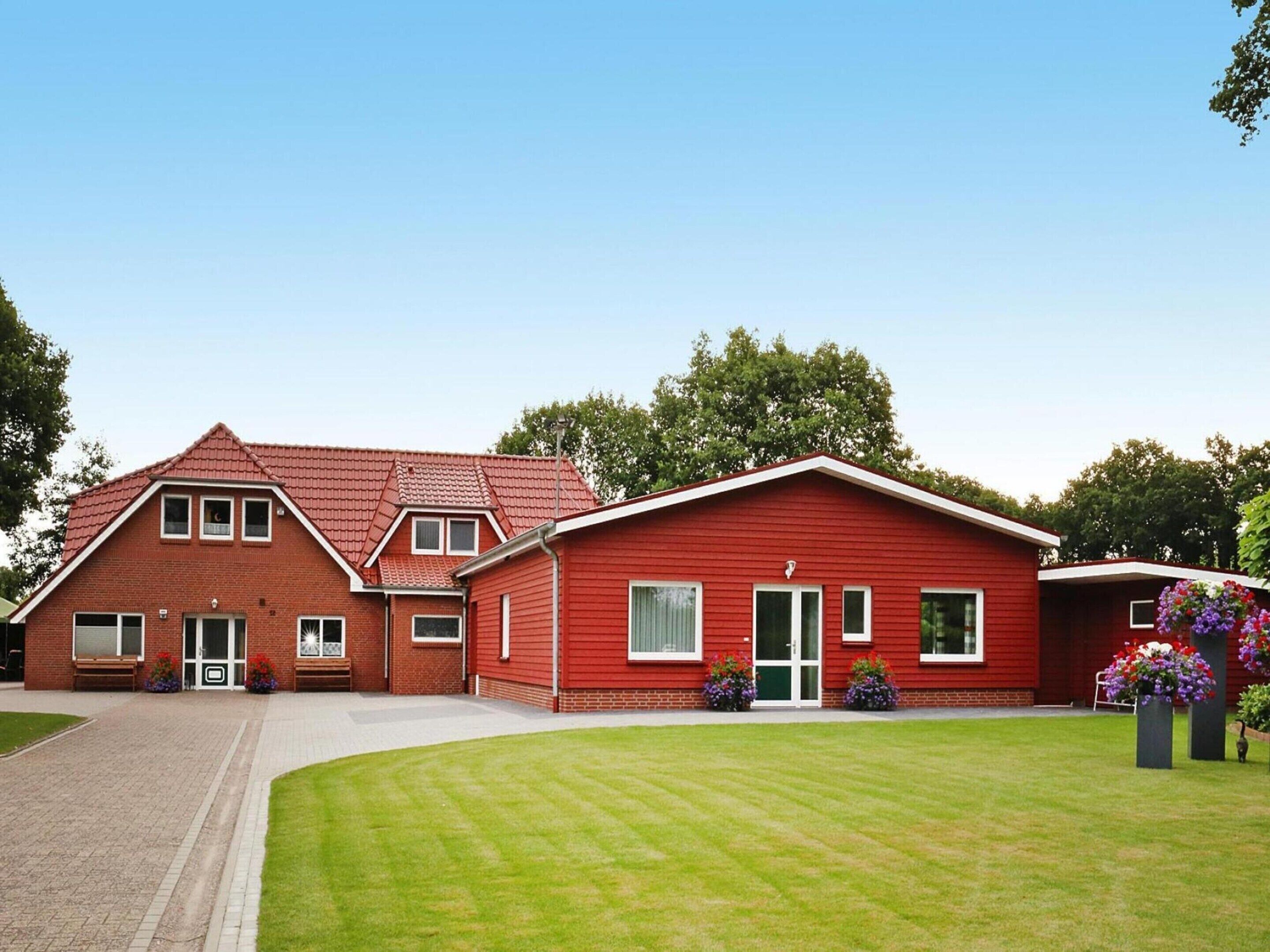 A red brick building with a sloped roof, a front entrance with a door, and a small porch area.
