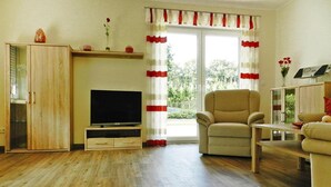 A living room with a TV, a sofa, a chair, and a cabinet. - Ferienwohnung Landblick, Rastede (Rastede)