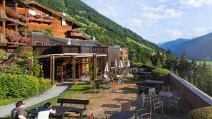 A wooden building with outdoor seating and a view of a mountainous landscape. - Apartment in Matrei in Osttirol With a Washing Machine (Matrei in Osttirol)