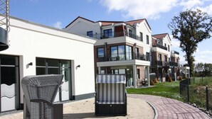 Un edificio residenziale moderno con un vialetto curvo in mattoni, posti a sedere all'aperto e un grande albero.