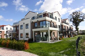 A modern multi-story residential building with balconies, large windows, and a covered outdoor seating area. - Apartments in the Avalon Hotel Bellevue, Fehmarn (Fehmarn)