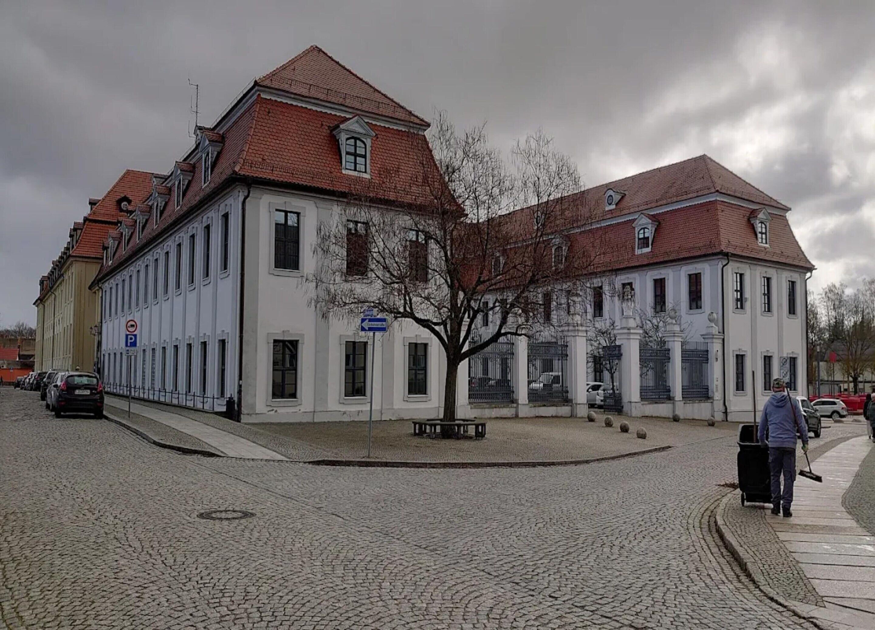 A historic building with a symmetrical facade, large windows, and a central tree.