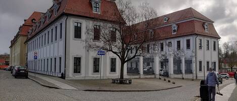A historic building with a symmetrical facade, large windows, and a central tree.