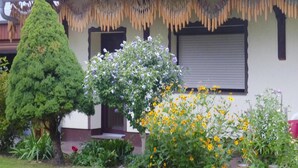 A house with a well-maintained garden, a large coniferous tree, and flowering plants. - Bungalow in Lubben With a Terrace (Lübben (Spreewald))