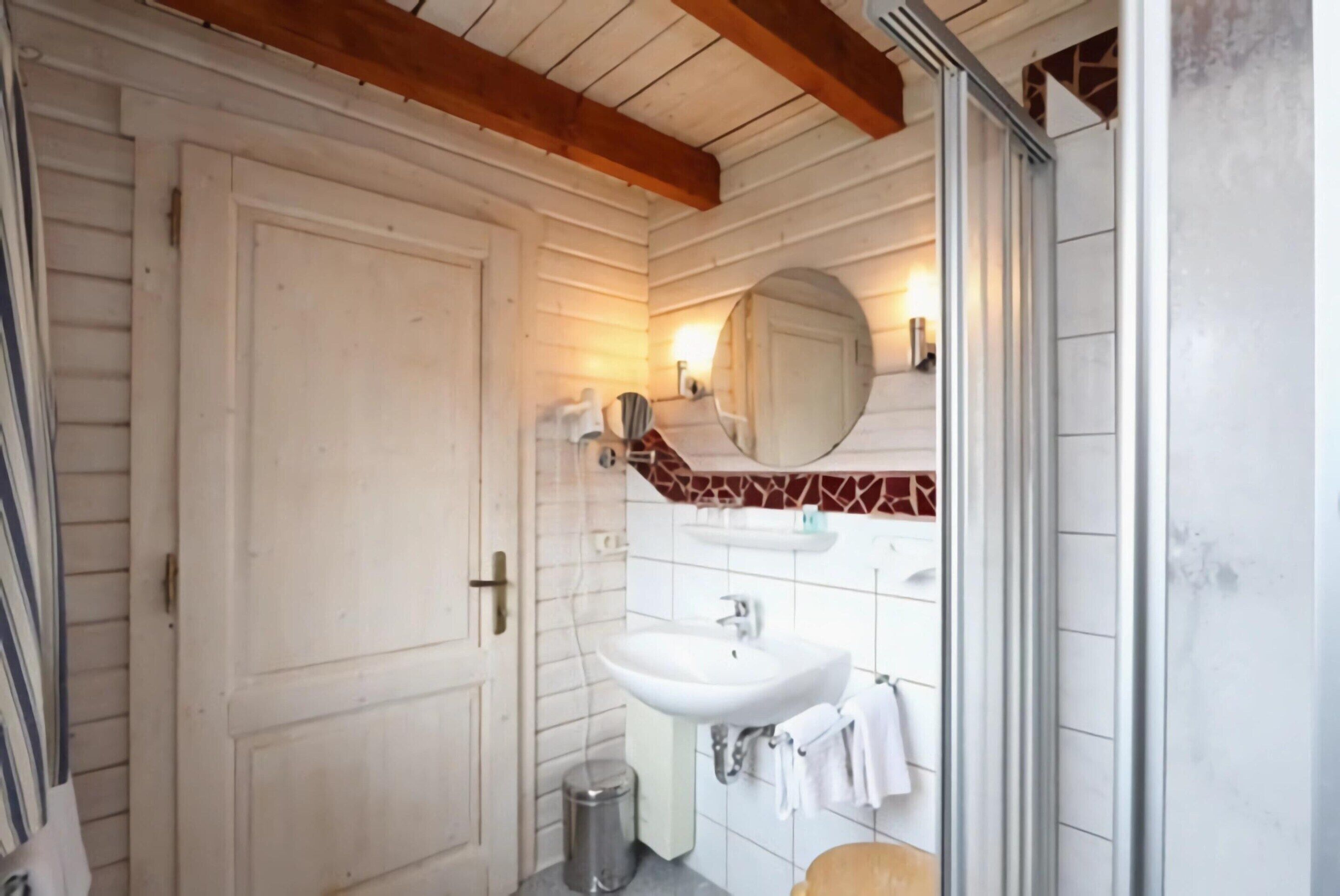 A bathroom with a white sink, a mirror, and a tiled wall.