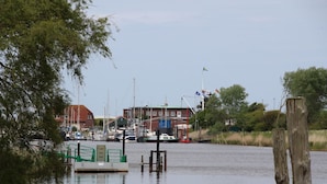 Un puerto deportivo con barcos amarrados, un barco verde en primer plano y edificios al fondo.