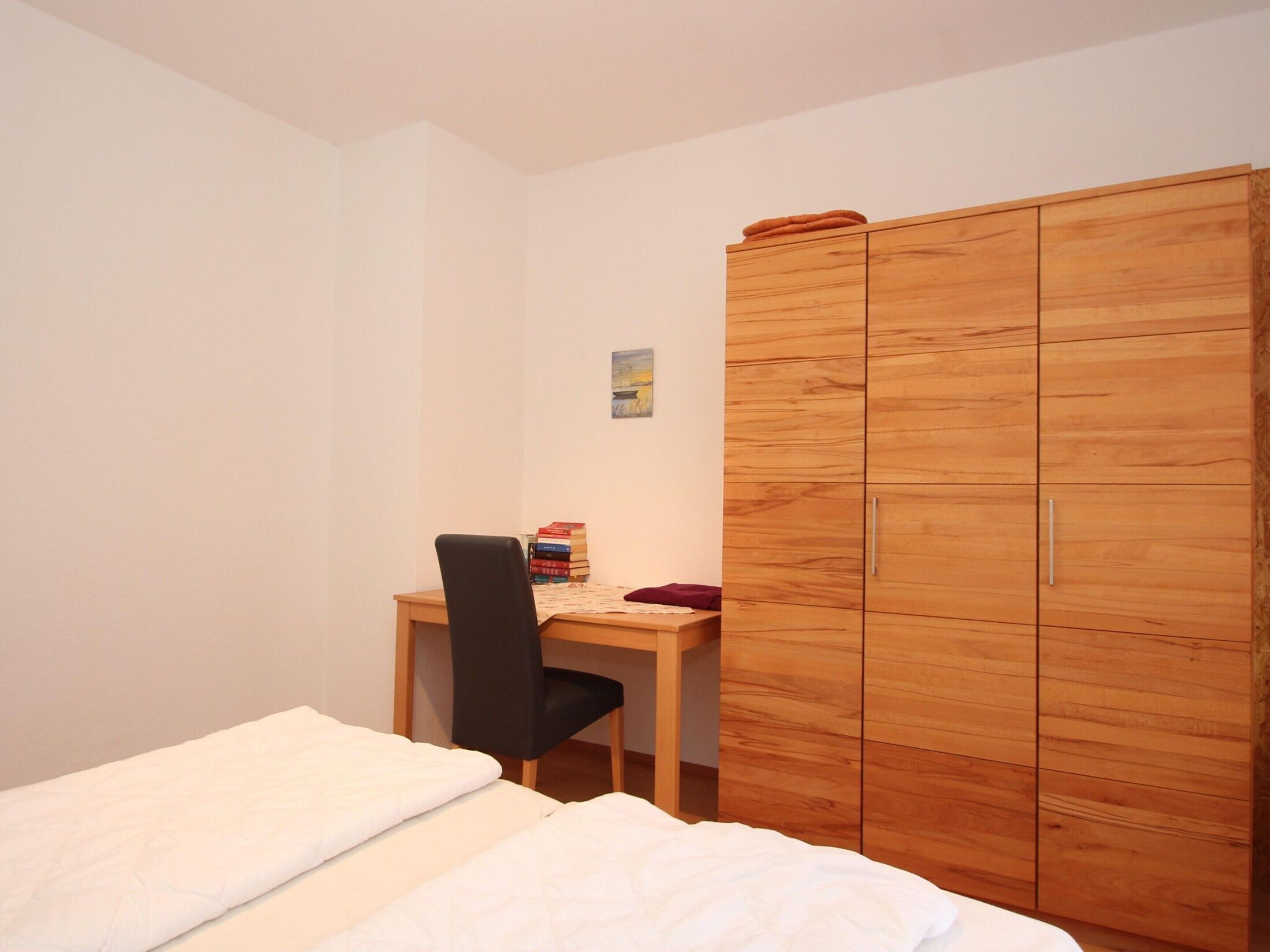 A bedroom with a bed, a desk, and a wardrobe.