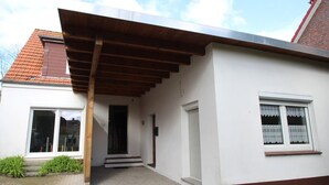 Una casa de un piso con un porche cubierto, una puerta principal y un pequeño jardín delantero.