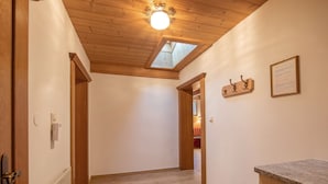 A hallway with wooden flooring, a skylight, a radiator, a door, a coat rack, and a framed certificate on the wall. - Apartment in Neustift With a ski Storage (Neustift Im Stubaital)