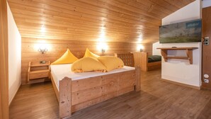 A wooden-paneled bedroom with a bed, bedside tables, a TV, and a wall-mounted shelf. - Apartment in Neustift With a ski Storage (Neustift Im Stubaital)