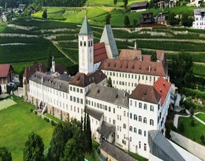 A large, historic building with multiple wings and a prominent tower, surrounded by lush green fields. - Apartment in Neustift With a ski Storage (Neustift Im Stubaital)