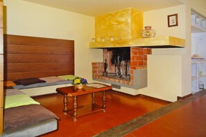 A living room with a fireplace, a sofa, a coffee table, and a wooden headboard. - Agriturismo La Scopa, Montaione (Montaione)