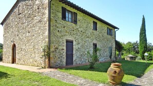 A stone building with a tiled roof, a wooden door, and a small garden with a large pot. - Agriturismo La Scopa, Montaione (Montaione)