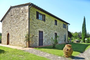 A stone building with a tiled roof, a wooden door, and a small garden with a large pot. - Agriturismo La Scopa, Montaione (Montaione)
