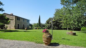 A stone building with a paved pathway leading to a large terracotta pot with flowers. - Agriturismo La Scopa, Montaione (Montaione)