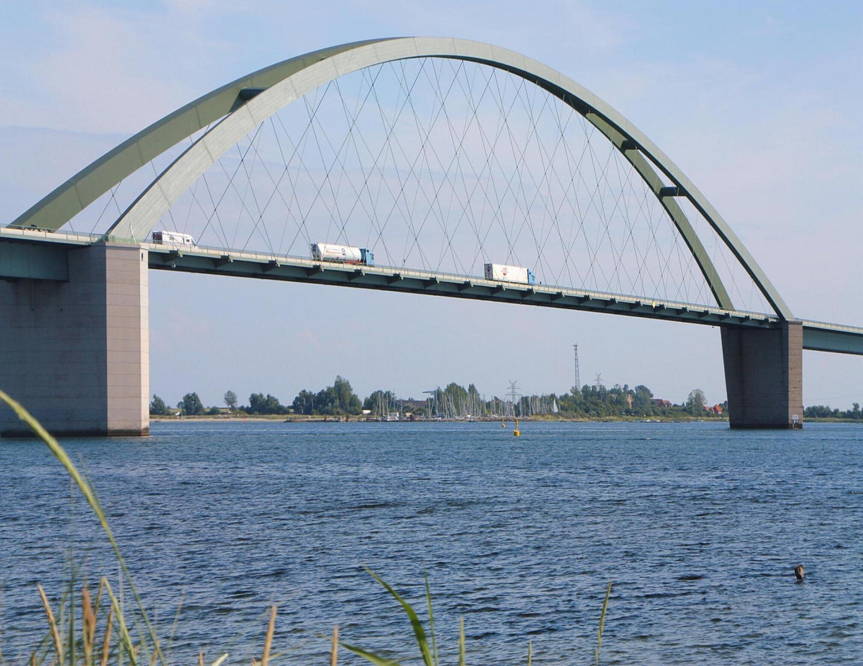 A large arched bridge over a body of water with vehicles crossing.
