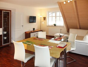 Un comedor con una mesa, sillas, un televisor y una ventana con vistas.