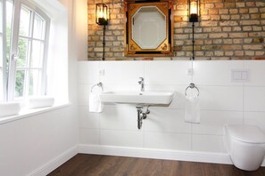 A bathroom with a white sink, two towel racks, a white toilet, and a window with a white towel on the sill. - Holiday Home Birgit, Wendorf (Kuhlen-Wendorf)