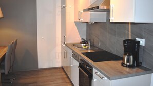 Una cocina moderna con un lavamanos de acero inoxidable, una cafetera y un horno empotrado.