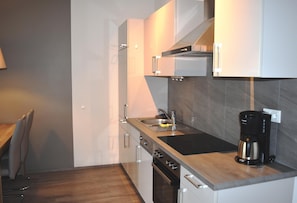 A modern kitchen with a stainless steel sink, a coffee maker, and a built-in oven. - Apartment in Lubben Near the Water (Lübben (Spreewald))