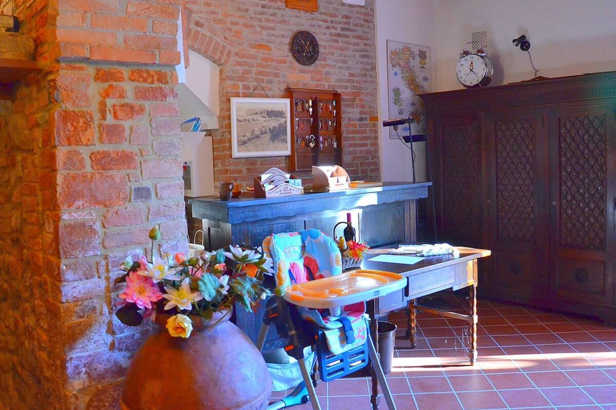 A rustic kitchen with a brick wall, wooden beams, and a tiled floor.