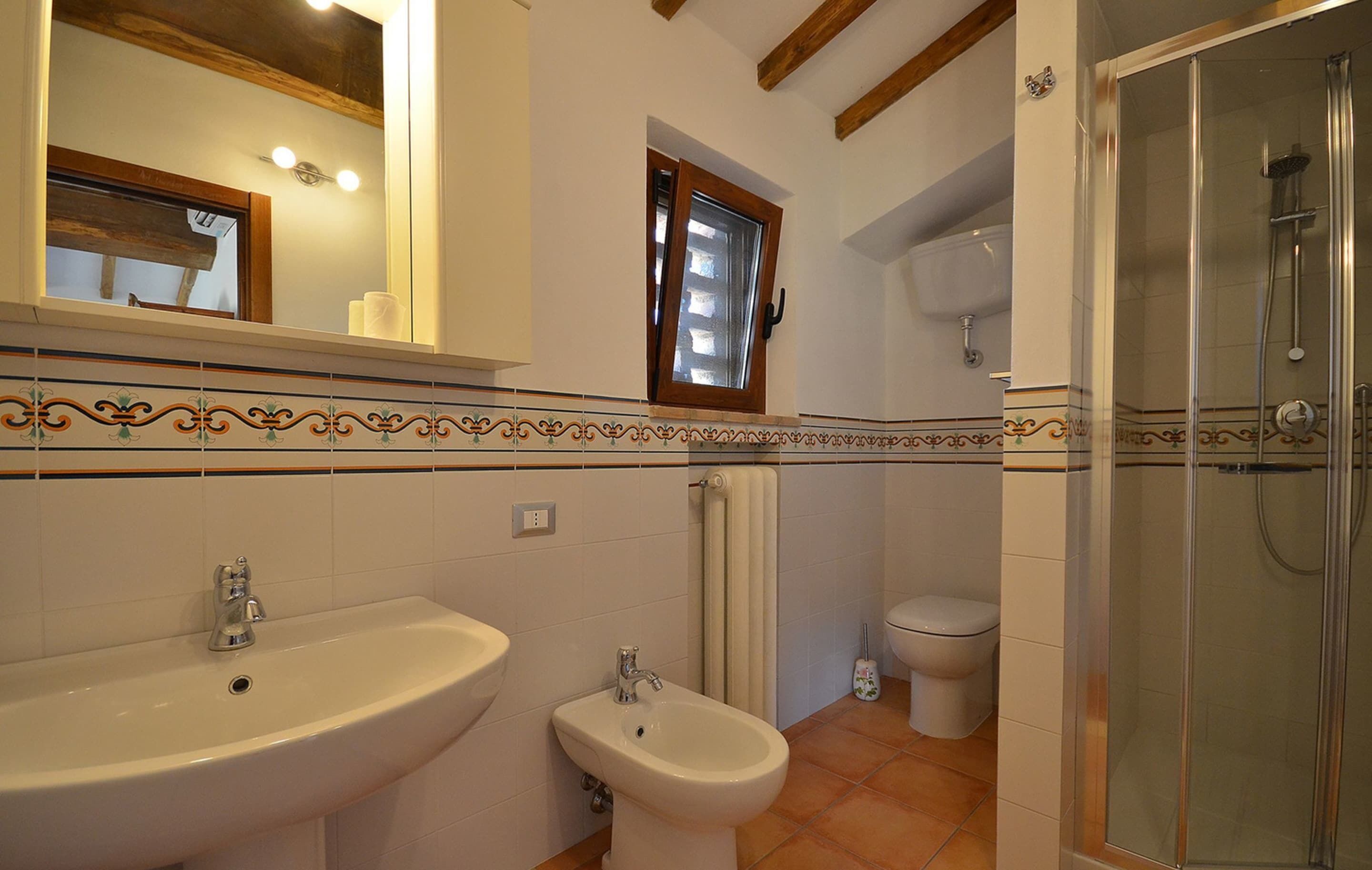 Un baño con lavabo, bidé, inodoro y ducha con mampara de vidrio.