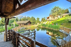 A wooden deck overlooking a pond with a mountain backdrop. - Chalet in Neukirchen (Neukirchen am Grossvenediger)