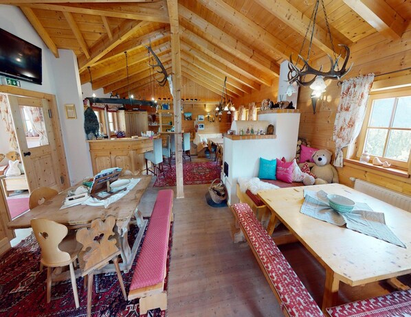 Interior acolhedor de cabana com vigas de madeira, um espaço de bar e área de refeições com bancos.