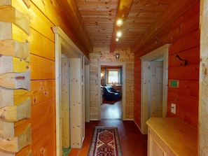 A wooden interior hallway with a rug, a blue chair, and a window with curtains. - Chalet in Neukirchen (Neukirchen am Grossvenediger)