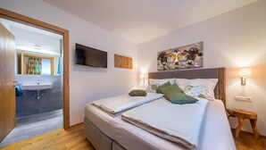 Ein Schlafzimmer mit einem Bett, einem Fernseher, einem Gemälde und einer Nachttischlampe.